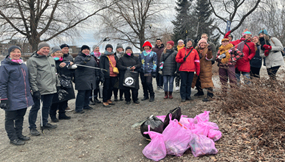 People gathered in line in a park, a pile of pink trash bags in the middle.